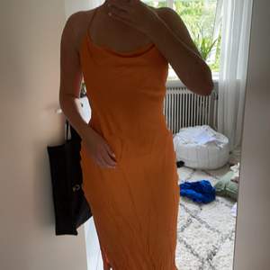 Knälång klänning i jättefin orange färg med knytning i ryggen och slits på vänster sida 