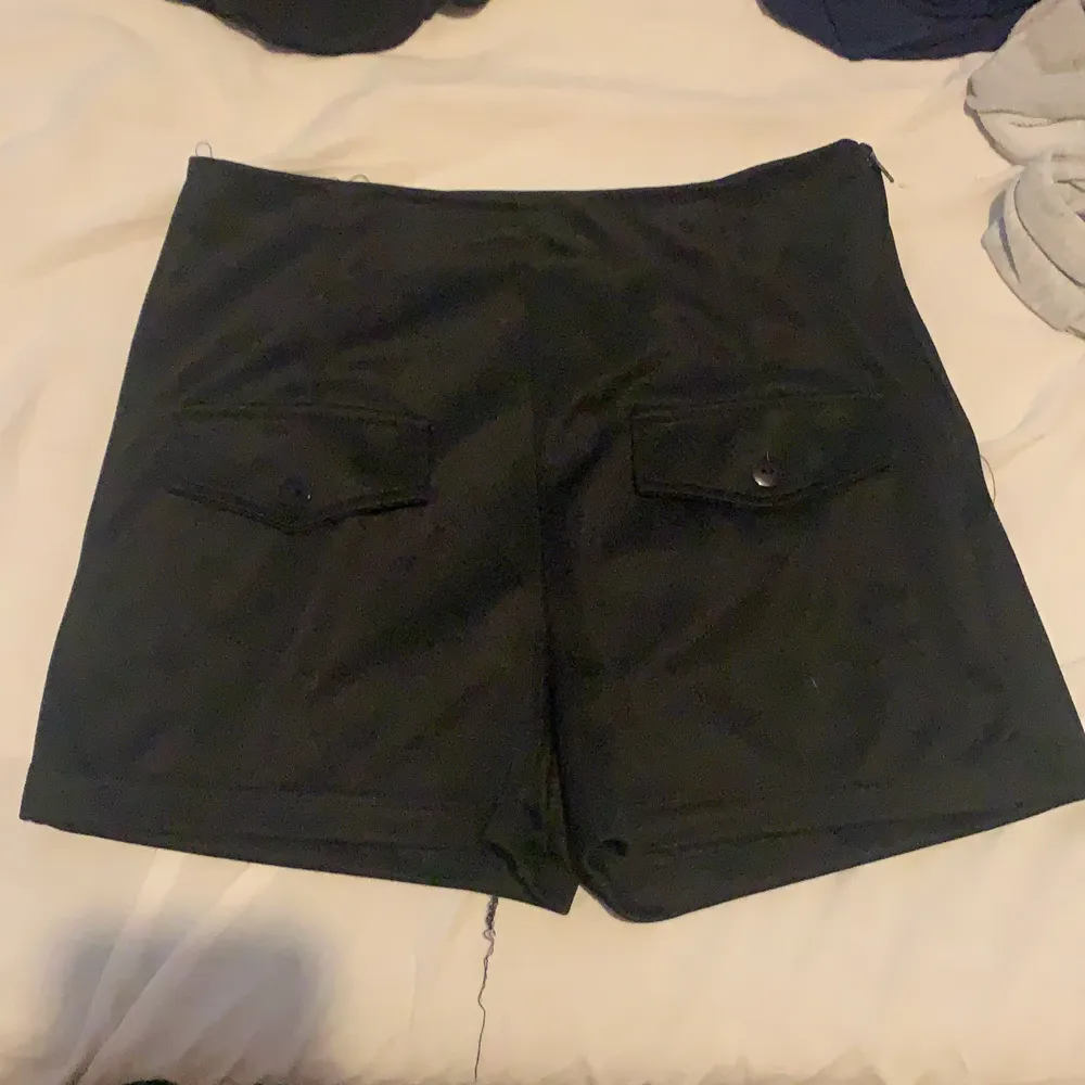 Svarta shorts med fickor där fram och en dragkedja på sidan . Shorts.