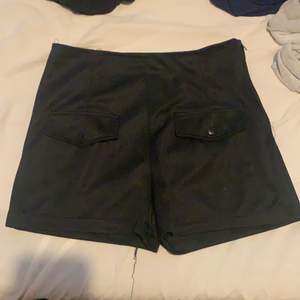 Svarta shorts med fickor där fram och en dragkedja på sidan 
