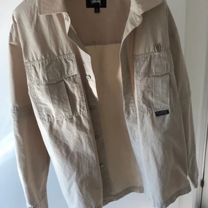 Stussy overshirt  - Beige OVERSHIRT från Stussy, man kan även göra den till en kortärmad skjorta som ni kan se på sista bilden. Strl S. Ordinarie pris 1099kr. Riktigt bra skick, använt ca 5 gånger. Först till kvarn❤️ exl frakt