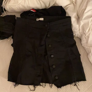 Kjol  - En svart jeanse kjol ifrån Gina tricot i storlek 40. Knappar hela vägen och fransar ish längst ner