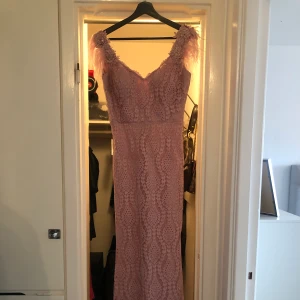 Festklänning  - Storlek 36/38, en liten brun utan sol fläck innanför. Släp ingår, fjädrar på axlarna. 