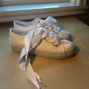 Vita skor med skosnören gjorda av ett blankt material (påminner om siden). Skorna är i storlek 39, säljer på grund av att dom är för stora. Dom har hög sula nästan platå. 