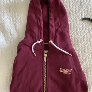 Superdry hoodie - Säljer en hoodie från superdry med jättefina gulddetaljer! Använd fåtal gånger och i jättebra skick. Orginalpris 999kr säljer för 250kr!