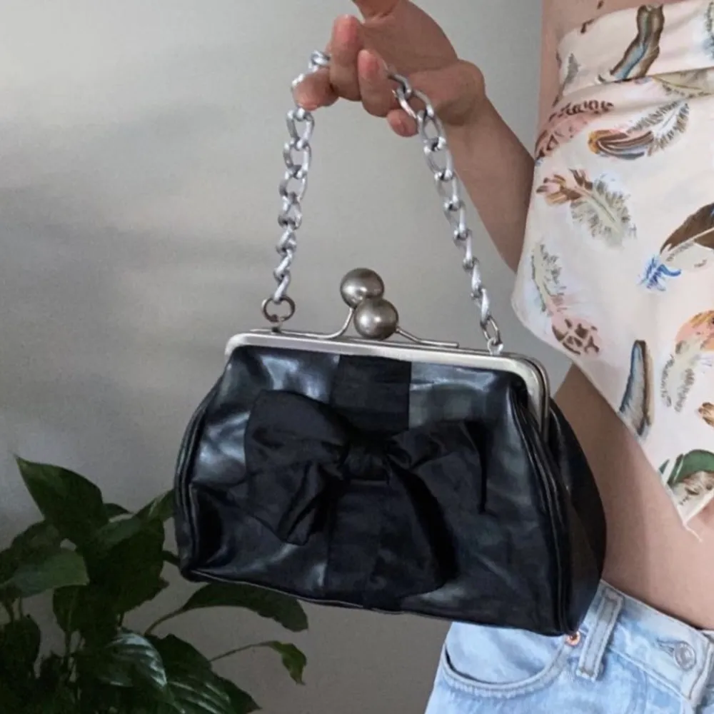 En svart handväska med rosett på framsidan och leopardmönster på insidan. Rymlig och riktigt stilig! Köpt second hand men sällan använd. Från märket colour&beauty. Frakt tillkommer, kan mötas upp i stockholm❤️ 2 FÖR 1 PÅ ALLT. Laukut & Käsilaukut.