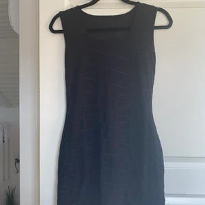 Svart klänning  - Svart klänning med detaljerade streck, med liten slits.  stl m/L