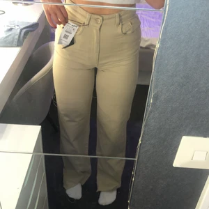 Vida Beiga Jeans ifrån Asos - Ett par vida beiga jeans ifrån Asos i storlek 36. Dem sitter väldigt bra, Är lite långa för mig som är 165 cm! Säljer dom då de är lite långa för mig. De är helt oanvända och prislappen är kvar. Köpte de för 499 kr men säljer de för 200