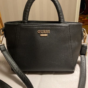 Guess väska  - Väska från Guess. Storlek mått 24*17 cm. Handtag och axelrem . Axelrem ställbar o kan tas bort . Använd men knappt synligt . Köpt i canada. Garanterat äkta . Fler bilder mm skickad om så önskas 