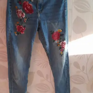 ljusblå skinny jeans med röd och rosa rosor, inga fläckar och är i bra skick. (möjligt att pruta till passande pris)