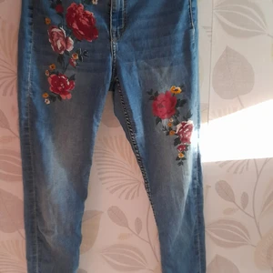 skinny jeans med ros detalj strl 36 - ljusblå skinny jeans med röd och rosa rosor, inga fläckar och är i bra skick. (möjligt att pruta till passande pris)