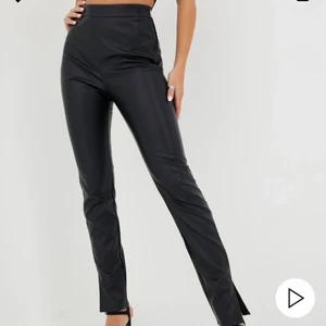 Skinnbyxor med slits - Svarta byxor i PU-material från Nelly. Sällan använda, köpta för 399kr