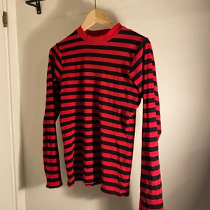 Röd och svartrandig tröja - En röd- och svartrandig tröja med tajt passform och slits i ärmen.