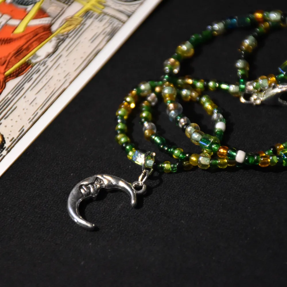 Ett enkelt halsband med gröna glaspärlor och en silvrig månberlock. Det finns endast ett! . Accessoarer.