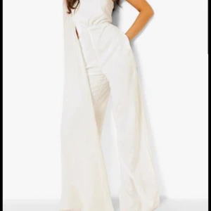 Vit jumpsuit byxdress Boohoo 34/XS lång vida ben one shoulder - Vit (se färg på bild 2) jumpsuit/byxdress från Boohoo. Storlek XS/34. Nyskick. Tagg kvar. Precis så fin som den ser ut. Långt släp över axeln. Nypris 380.-