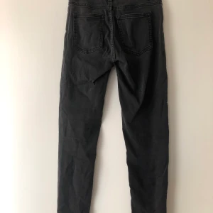 Gråa jeans - Välanvända jeans som är lite slitna pga användning med dragkedjor längst ner