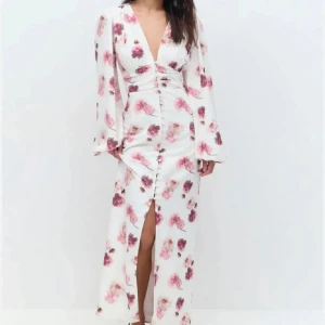 Vit långklänning med blommigt mönster och v-ringning - Klänning från Gina tricot. Helt ny aldrig använd. Storlek 34