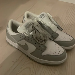 Nike Dunk Low i vitt och grått - Säljer ett par Nike Dunk Low sneakers i vitt och ljusgrått.