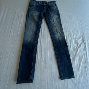 Replay jeans  - Säljer ett par klassiska blå jeans från Replay med raka ben och snyggt slitna detaljer framtill. Jeansen har normal passform och fem fickor. Perfekta för dig som gillar en tidlös stil.