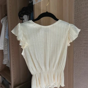 Ljus gul ribbad blus från Pull&Bear - Säljer en söt ljus gul ribbad blus från Pull&Bear med volangärmar och resår i midjan som ger en fin form. Perfekt till sommaren och enkel att matcha med både jeans och kjol.
