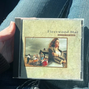 Fleetwood Mac - Behind The Mask - CD-albumet 'Behind The Mask' av Fleetwood Mac. Omslaget har en bild på en kvinna framför ett hus och bandmedlemmarna syns på baksidan. Albumet innehåller 13 låtar och ges ut av Warner Bros. Perfekt för dig som gillar klassisk rock. Helt orepad skiva! 