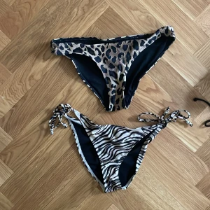 Två bikiniunderdelar med djurmönster - Säljer två snygga bikiniunderdelar, en med leopardmönster och en med zebramönster. Leopardunderdelen har klassisk passform medan zebramodellen har knyt i sidorna för justerbar passform. Perfekta för sommaren! Totalt 70 kr för båda.