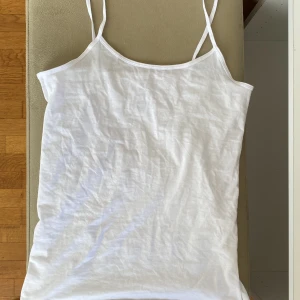 Vit linnetopp med smala axelband - Säljer en enkel och fräsch vit linnetopp med smala axelband. Perfekt till sommaren och lätt att matcha med olika outfits. 