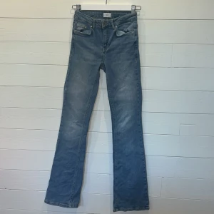 LjusBlå bootcut jeans från Grunt - Säljer ett par klassiska ljusblå jeans från Grunt med bootcut-passform. Jeansen har fem fickor, gylf med dragkedja och knapp samt normal midja. Perfekta för dig som gillar en tidlös denimstil. Lappen där storleken står är bortklippt, men om jag jämför med andra jeans som jag har borde detta vara 32.