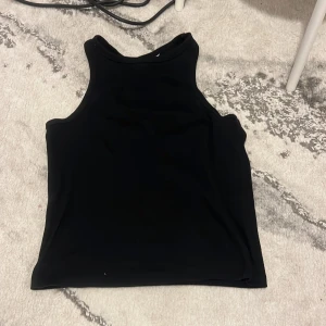 Svart linnetopp från H&M - Säljer en svart, ärmlös linnetopp från H&M. Toppen har en klassisk rak passform med rund halsringning och är tillverkad i mjukt material. Perfekt att matcha med jeans eller kjol.