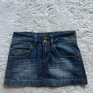 Low waist jeanskjol!! - Säljer en jätte snygg jeanskjol från CADA DIA i tvättad blå denim i storlek XXS. Kjolen är kort och lågmidjad med dekorativa nitar som blommönster på bakfickorna. Perfekt inför sommaren💗💗