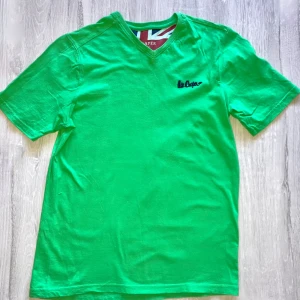 Grön t-shirt med v-ringning från Lee Cooper - Säljer en grön t-shirt från Lee Cooper med v-ringning och liten broderad logga på bröstet. T-shirten är i 100% bomull och har korta ärmar. Perfekt för en avslappnad stil.