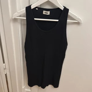 Svart ribbad linnetopp från Réunion - En svart ribbad linnetopp från Réunion i storlek medium. Toppen har en klassisk rund halsringning och är ärmlös, perfekt för varma dagar eller som lager under andra plagg.