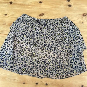 Leopardmönstrad kjol från Honey Punch - Säljer en kort kjol från Honey Punch med leopardmönster i grått, svart, beige och gult. Kjolen har volang och även resår i midjan och är tillverkad i ett tunt, lätt material som ger en luftig känsla. Perfekt kjol för sommaren! Pris kan diskuteras vid snabb affär! 🌸