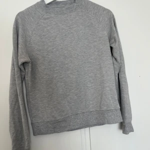 Grå sweatshirt från STAY - Säljer en enkel och stilren grå sweatshirt från STAY i storlek XS. Tröjan har rund halsringning, långa ärmar och ribbade muddar vid ärmslut och nederkant. Perfekt för en avslappnad look.