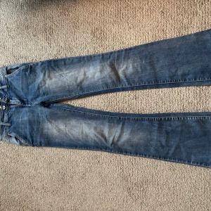 Lågmidjade jeans - Klassiska blå jeans med bootcut och lågmidjad passform. dragkedja och knapp i midjan. Perfekta för en avslappnad stil och passar till det mesta.