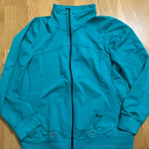 Svarta mjukisbyxor med turkos mjukiskofta - Svarta mjukisbyxor från Reflex med turkosa sömdetaljer vid fickorna. Byxorna har en rak passform och är tillverkade i mjukt bomullsmaterial, perfekta för en avslappnad stil. Mjukiskoftan följer med.