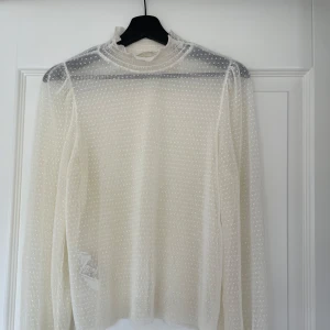 Vit blus med prickigt mönster - Säljer en vit blus med små prickar och lite hög hals. Blusen har långa ärmar. Perfekt för lager-på-lager. Storlek L men passar bra på M