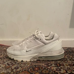 Vita Nike sneakers med mesh och synlig luftbubbla - Säljer ett par vita Nike sneakers med mesh-överdel och synlig luftbubbla i sulan. Skorna har snörning, flera små swoosh-loggor och en modern, chunky design. Perfekta för dig som gillar sportig och stilren look.