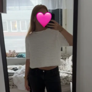 Vit stickad croppad tröja - Säljer en vit stickad croppad tröja med korta ärmar. Tröjan har ett luftigt och lätt hålmönster, perfekt för varmare dagar. Enkel och stilren design som passar till mycket.