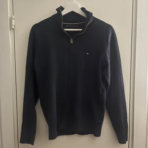 Mörkblå halvzip tröja från Tommy Hilfiger - Säljer en mörkblå långärmad tröja från Tommy Hilfiger i premium bomull. Tröjan är en halvzip och har en liten broderad logga på bröstet. Perfekt för en stilren och klassisk look.