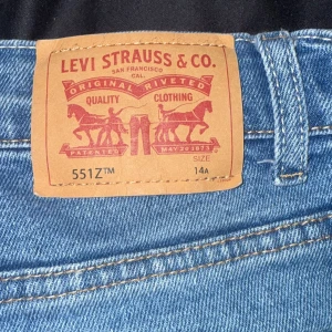 Levi's 551Z ljusblå jeans - Ljusblå Levi's 551Z jeans med klassisk femficksdesign och dragkedja. Jeansen har raka ben och normal passform, tillverkade i slitstarkt bomullsjeans. Perfekta för dig som gillar en tidlös och avslappnad look.