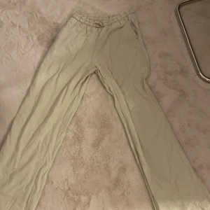 Beiga linnebyxor från Lindex Kids - Snygga och luftiga beiga linnebyxor från Lindex Kids i storlek 164. Byxorna har resår och snörning i midjan samt raka, vida ben. Perfekta för en chill och avslappnad stil.