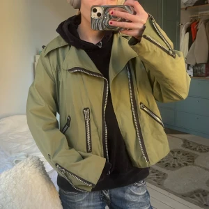 Olivgrön bomberjacka med dragkedjor - Säljer en olivgrön bomberjacka med flera grova dragkedjor och coola detaljer. Står ingen storlek men skulle säga s/m