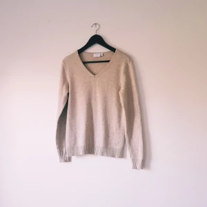 Beige stickad v-ringad tröja från Vila strl M - Mysig beige stickad tröja från Vila med v-ringning och långa ärmar. Perfekt för lager-på-lager och passar till både jeans och kjol. Ribbstickade muddar vid ärmslut och nederkant ger en snygg finish.  Helt skick dock nopprig