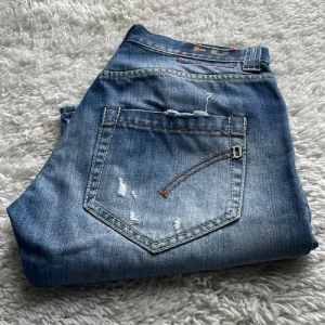 Dondup - Snygga blå jeans med slitna detaljer och klassisk bakficka. Jeansen har en tvättad look och kontrastsömmar som ger en cool vibe. Perfekta för dig som gillar en avslappnad och trendig stil.