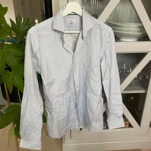 Ljusblå mönstrad skjorta från Bläck - Snygg ljusblå skjorta från Bläck med diskret geometriskt mönster i blått. Skräddarsydd passform och klassisk krage. Perfekt för dig som gillar stilrena detaljer och vill ha en skjorta som sticker ut lite lagom.