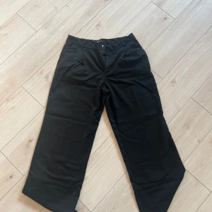 Svarta kostymbyxor LCW Vision - Stilrena svarta kostymbyxor från LCW Vision i rak modell. Byxorna har klassisk passform med hällor för bälte och diskret knäppning framtill. Perfekta för en clean och dressad look.