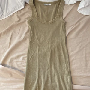 Beige ribbad klänning från Zara - Snygg beige ribbad klänning från Zara i figurnära modell. Ärmlös med breda axelband och rundad halsringning. Perfekt för en enkel och stilren look, lätt att matcha med accessoarer.