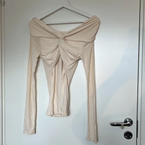 Beige offshoulder topp Gina Tricot XS - Supersnygg beige offshoulder topp från Gina Tricot i storlek XS. Långärmad modell med twistad detalj framtill. Endast använd fåtal gånger, inga defekter.