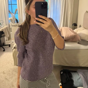 Lila stickad tröja med trekvartsärm - Supermysig lila stickad tröja med trekvartsärm och ribbade muddar. Tröjan har en rak passform och är perfekt för lager-på-lager under kyliga dagar. Snygg att styla med både jeans och kjol för en chill vibe.