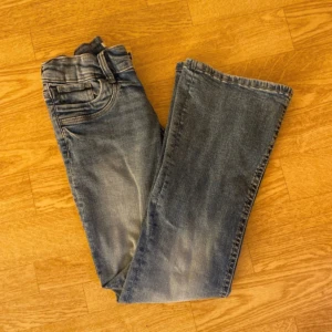 Blå lågmidjade bootcut jeans  - Snygga blå jeans från Gina Young i storlek 158 med bootcut-modell och även lågmidjade. Jeansen har en något ljusare tvätt på låren och är tillverkade i mjukt denimtyg som ger en avslappnad vibe. Perfekt för kalla sommardagar men även till höst och vinter. Jenssen är HELT nya , endast provade , men råkade ta bort prislappen innan jag testade dem så det går inte att lämna tillbaka. Original pris är runt 350kr. 